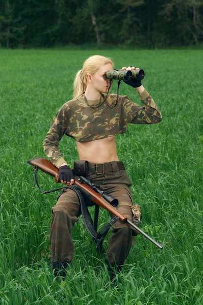 Attraktives Jägermädchen mit Jagdkarabiner beim Blick ins Fernglas — Stockfoto