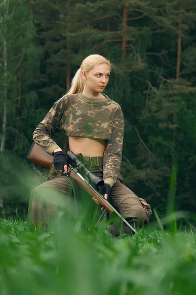 Atractiva chica cazadora con carabina de caza mirando hacia el trop — Foto de Stock