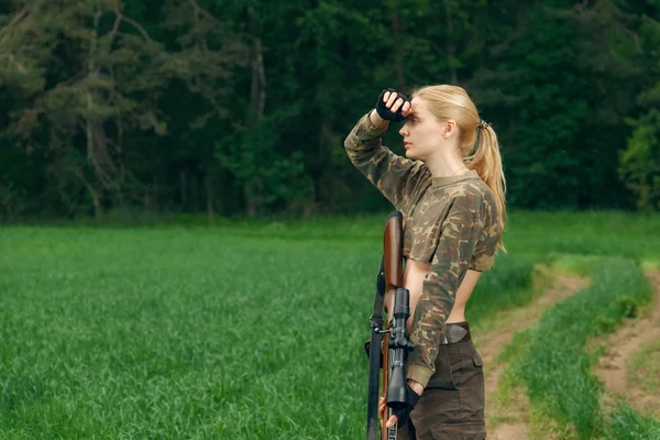 Menina caçador atraente com carabina de caça olhando para fora da tropa — Fotografia de Stock
