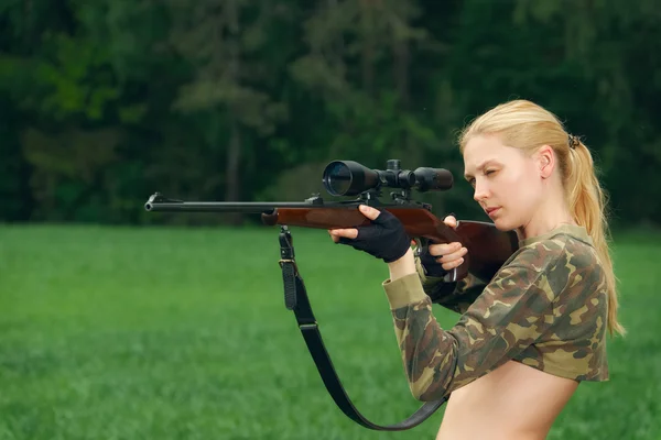 Menina caçador bonita apontando com rifle de caça na madeira exterior . — Fotografia de Stock
