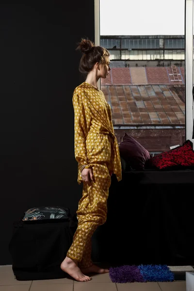 Pretty fashion model in silk pyjamas near window — Stock Photo, Image