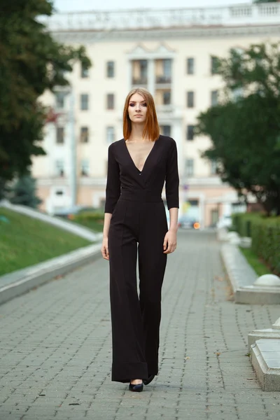 Elegante modelo de moda joven en negro en general con decolete profundo en el parque de la ciudad — Foto de Stock