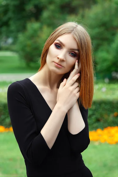 Stylisches junges Mode-Model in schwarzem Overall mit tiefem Dekollete im Stadtpark — Stockfoto