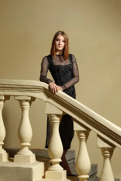 Ragazza in breve abito nero sulle scale con ringhiere — Foto Stock