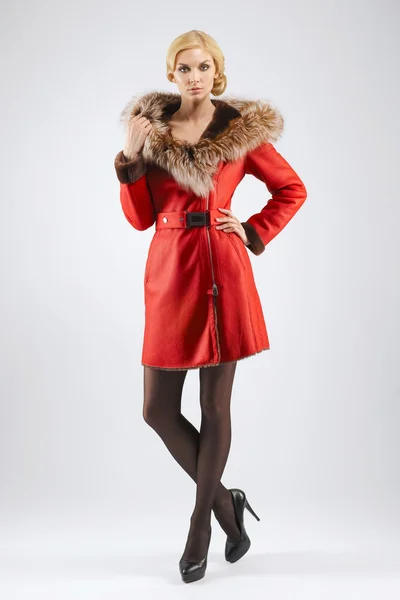 Attraktive Dame im kurzen roten Ledermantel mit Fellkapuze posiert — Stockfoto