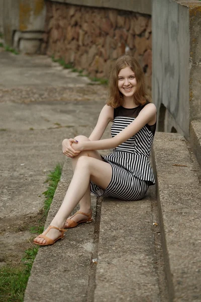 Όμορφη νεαρή έφηβη κοπέλα σε ριγέ φόρεμα κάθεται σε σκαλοπάτια — Φωτογραφία Αρχείου