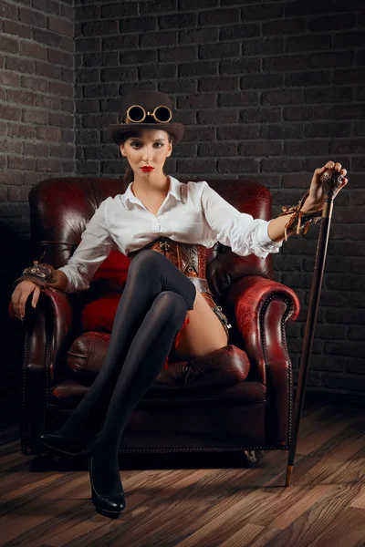 Porträt eines schönen Steampunk-Mädchens in Dessous und Strümpfen, das in einem alten Sessel sitzt. — Stockfoto