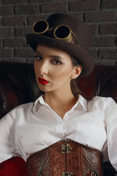 Retrato de cerca de una hermosa chica steampunk en lencería y medias sentadas en un sillón viejo . —  Fotos de Stock