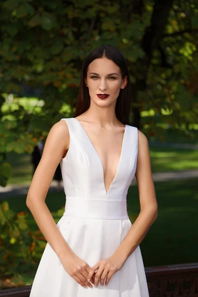 Derin bir yaka ile uzun beyaz elbiseli güzel kız. Moda — Stok fotoğraf