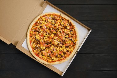 Biftek, domates, soğan ve karton pakette çedar peynirli pizzanın en üst görüntüsü.