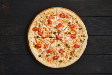 Karidesli pizza, somon, domates ve ahşap masa üzerinde kapari.