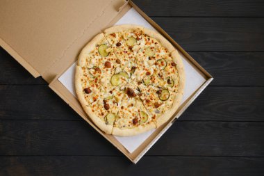 Tavuklu pizza, ballı mantar ve karton pakette salatalık turşusu.