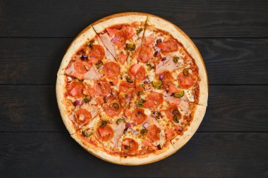 Biberli pizza, jambon, dolmalık biber, zeytin ve kırmızı soğanlı koyu ahşap masa.