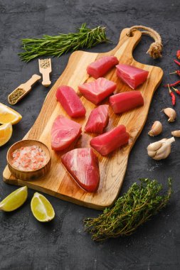 Taze ton balığı filetosu, baharat ve ahşap kesme tahtasının üzerinde bitkiler.