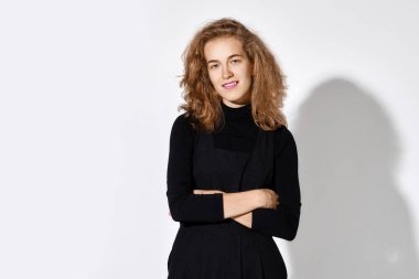 Elleri çapraz olan siyah kazaklı hoş bir genç kadın.