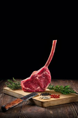 Raw juicy cowboy steak on wooden cutting board with spice clipart