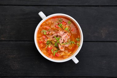 Kalın, baharatlı ve ekşi çorbadan oluşan, koyu ahşap masada sığır eti.