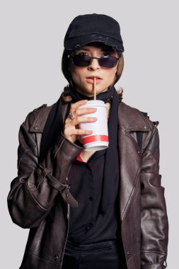 Deri ceketli, siyah bluzlu, ipek eşarplı ve kasketli bir kız.