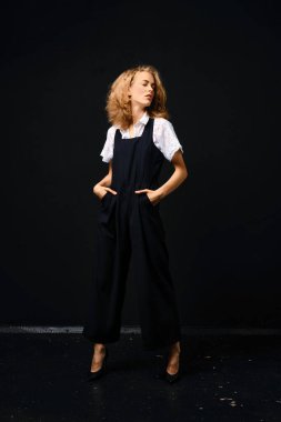 Siyah takım elbiseli, beyaz gömlekli, siyah arka planda güzel bir manken.