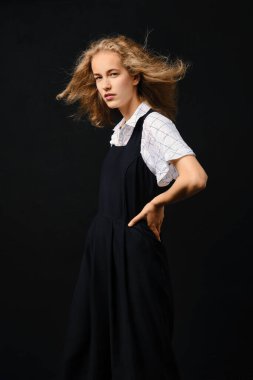 Siyah arka planda dalgalı saçları olan hoş bir genç kadın.