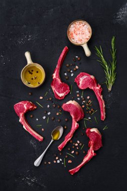 Kuzu pirzolası, baharat ve koyu arkaplanda otlar.