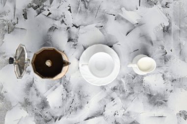 Gayzsr kahve makinesinin üst görünümü, soyut arka planda sütlü fincan ve demlik