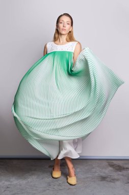 Açık renkli bir elbise sallayan modelin tam boy portresi. 