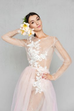 Elinde çiçeklerle dantelli şeffaf tül elbiseli güzel bir kız.