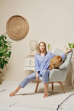 Neşeli genç bir kadın pofuduk tükürüğüyle koltukta oturuyor.