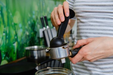 Kahve makinesinde öğütülmüş kahve yapan kadınların yakın görüntüsü.