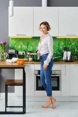 Mutlu genç bir kadın elinde kızarmış yumurta ve tavayla masaya gider.