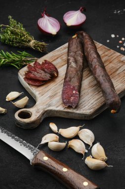Ahşap kesme tahtasının üzerinde kurutulmuş sığır eti sosisi.