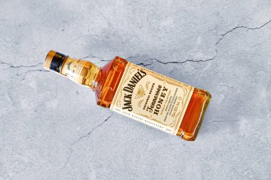 13 Nisan 2021, Minsk, Belarus - Bir şişe Jack Daniel 's Honey çatlamış beton arka planda yatıyor