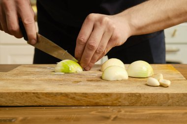 Soğan doğramanın yakın görüntüsü. Bıçakla soğan doğrayan erkek elleri..