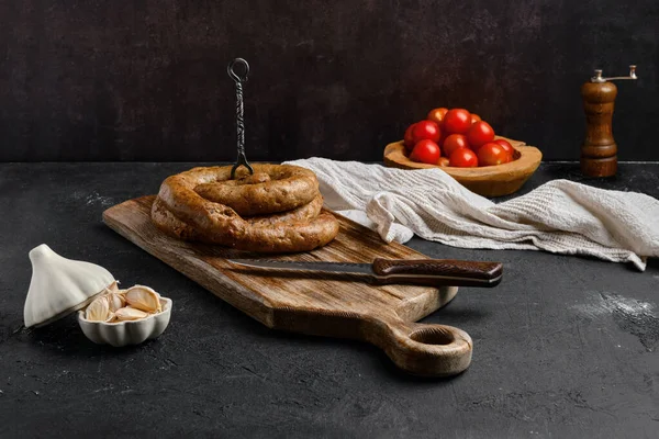 Horse meat sausage with garlic rolled on wooden cutting board