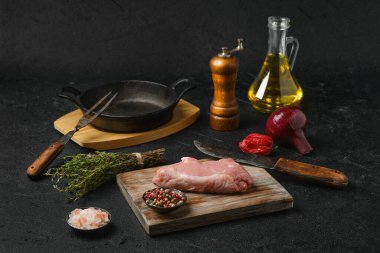 Çiğ biftek kemiği ve siyah arka planda yemek pişirmek için malzemeler.