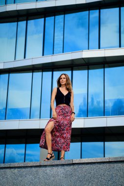 Genç bayan ofis binasının önünde duruyor.