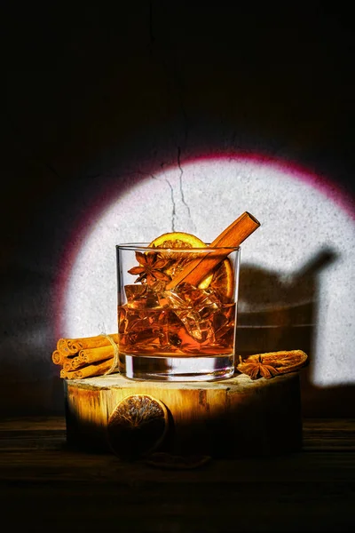 Konyak ve portakal likörüyle soğuk kokteyl, tarçın ve ahşap blokta yıldız anason.