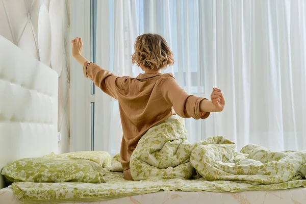 Vista Posterior Joven Mujer Estirando Los Brazos Sentada Cama Dormitorio —  Fotos de Stock