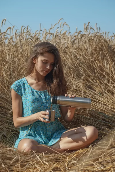 Hübsches Mädchen trinkt auf dem Feld — Stockfoto