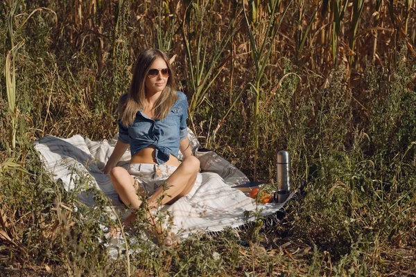 Menina atraente sentado no campo com livro — Fotografia de Stock