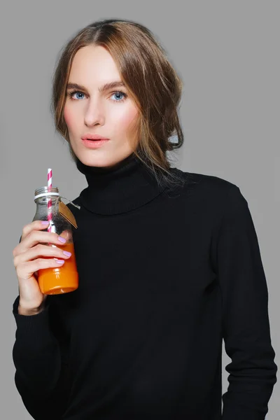 Menina bonita em pulôver preto com garrafa de suco na mão — Fotografia de Stock