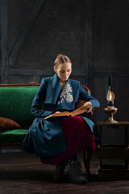 çekici Bayan antika gaz lambası yakınındaki antik kitap okuma