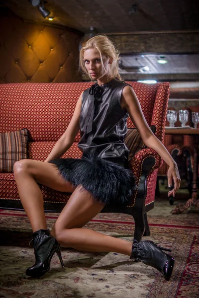 Attraente donna in abito corto nero e stivali di pelle in posa sul divano — Foto Stock