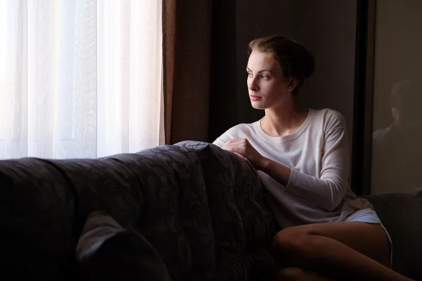 Красива жінка сидить біля вікна в темряві — стокове фото