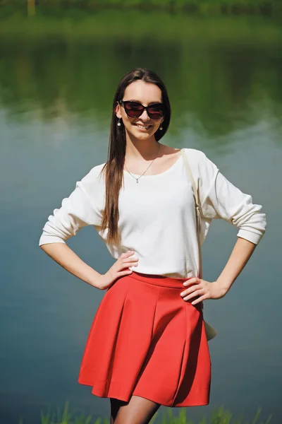 Chica bonita en gafas de sol en el parque de pie cerca del agua — Foto de Stock