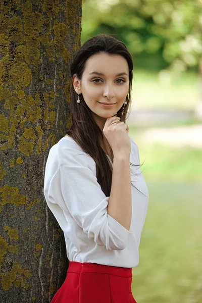 Chica bonita en el parque cerca del agua de pie delante del árbol — Foto de Stock