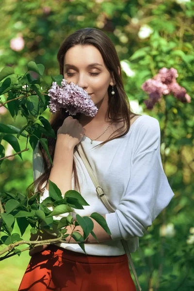 Chica bonita en el parque entre arbustos y flores — Foto de Stock
