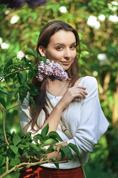 Chica bonita en el parque entre arbustos y flores — Foto de Stock