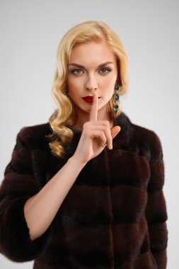 kahverengi kürk manto ile parmak üzerinde kırmızı dudakları çekici Bayan